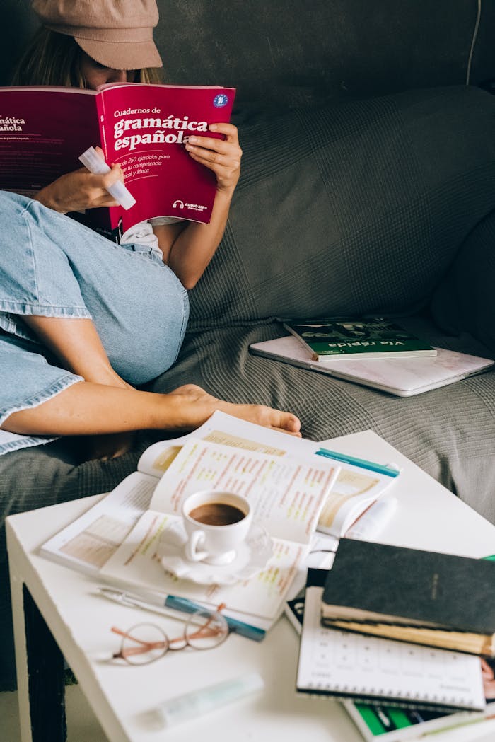 Woman studying Spanish grammar at home with coffee, books, and notes.
